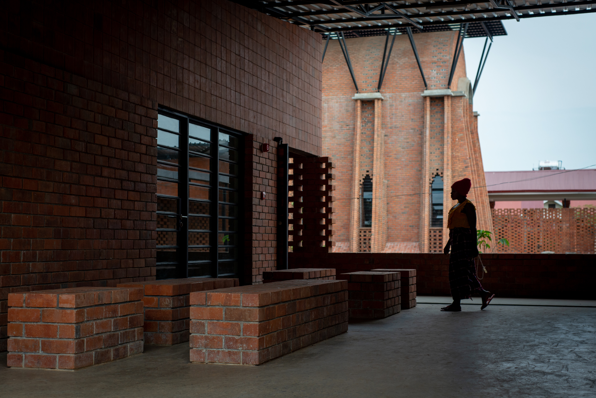 A person walking through the brick courtyard of Our Lady of Victoria Monastery in Uganda
